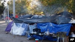 In this Dec. 3, 2019 photo, smoke rises from a wood fire stove at a tent encampment in a public park in Juarez, Mexico, a quarter of a mile away from a border crossing to El Paso, Texas. 