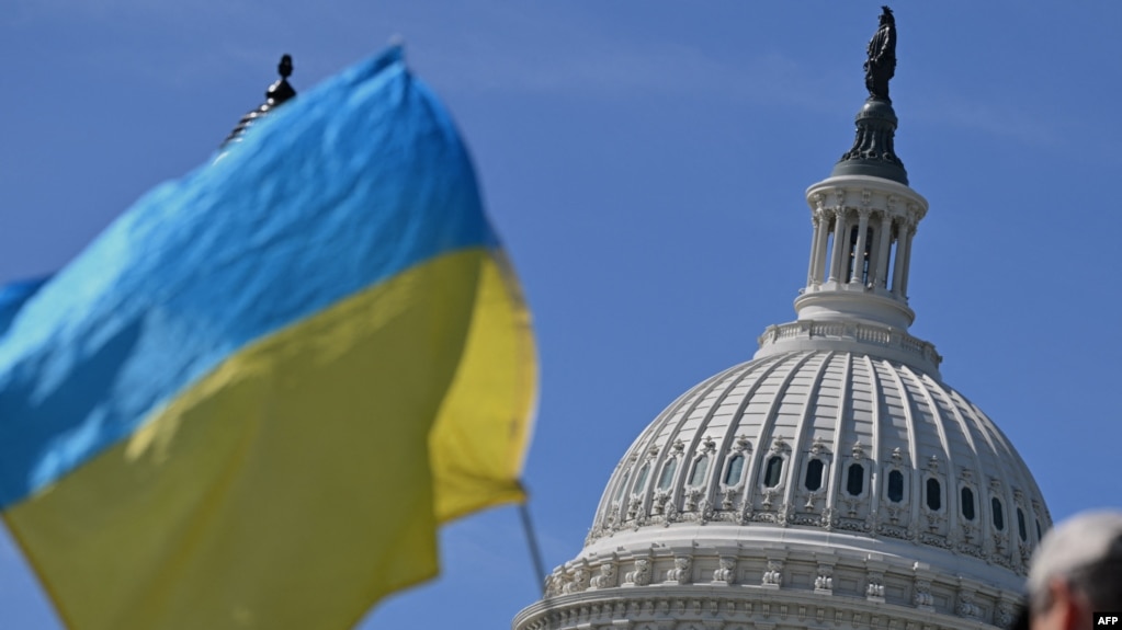 乌克兰支持者2024年4月23日在美国国会大楼外摇旗敦促国会通过950亿美元外援方案。（法新社）(photo:VOA)