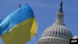 乌克兰支持者2024年4月23日在美国国会大楼外摇旗敦促国会通过950亿美元外援方案。（法新社）