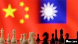 资料图片：这张图片摄于2023年4月11日，国际象棋子在展示的中国和台湾国旗前。