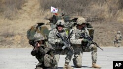 Des soldats sud-coréens de la 25e Division d'infanterie et des soldats sud-coréens prennent position lors d'une démonstration de l'exercice de tir interarmes dans le cadre de l'exercice militaire annuel conjoint Foal Eagle entre la Corée du Sud et les États-Unis au complexe polyvalent Rodriquez à Pocheon, au nord de Séoul, en Corée du Sud, le mercredi 25 mars 2015.