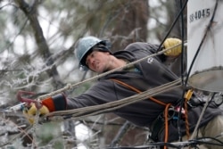 Lineman Charlie Hofmann stretches for a cable as he repairs a transformer in Jackson, Miss., Feb. 18, 2021.