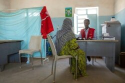 FILE - A Tigrayan woman who says she was gang-raped by Amhara fighters speaks to doctor-turned-refugee Tewodros Tefera at the Sudanese Red Crescent clinic in Hamdayet near the Sudan-Ethiopia border, eastern Sudan, March 23, 2021.