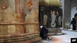 FILE—A woman pray at the Church of the Holy Sepulchre, where many Christians believe Jesus was crucified, buried and rose from the dead, in the Old City of Jerusalem, March 17, 2022.