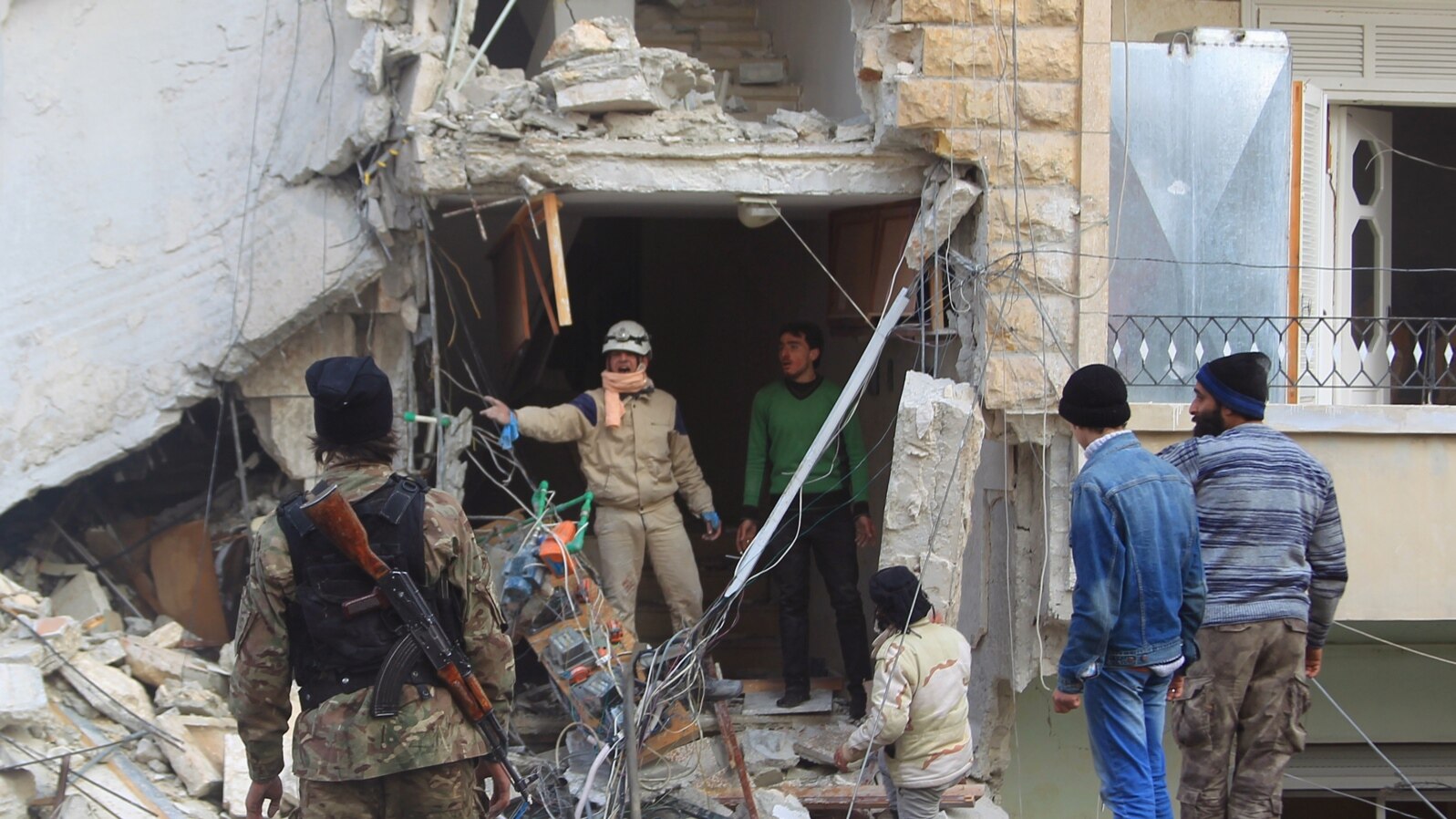 FILE - A civil defense member gestures toward a rebel fighter as they search for survivors at a site hit by what activists said were airstrikes carried out by the Russian Air Force in Idlib, Syria, Dec. 20, 2015.