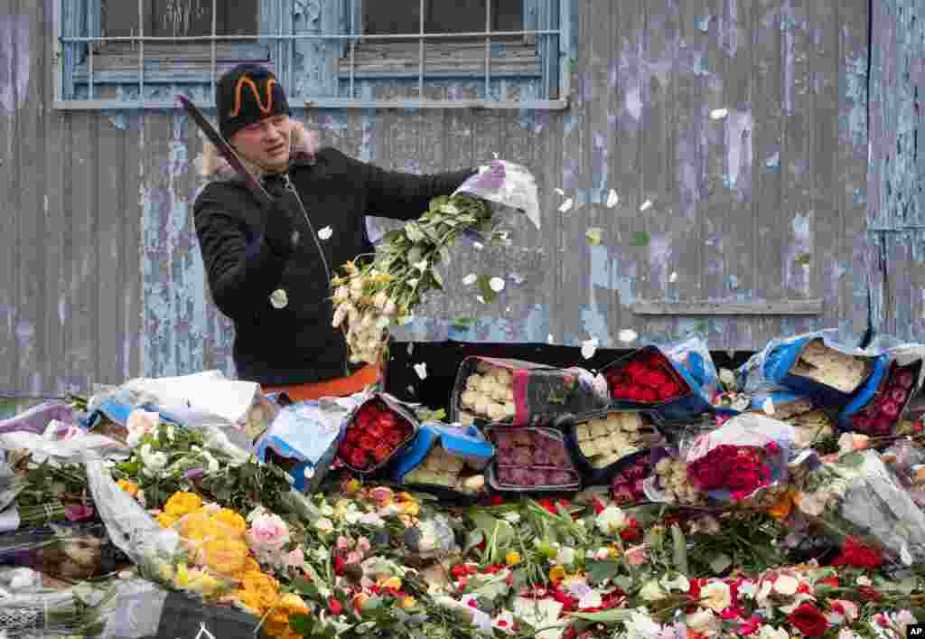 A flower shop employee cuts up unsold flowers in St. Petersburg, Russia. City authorities ordered to close non-grocery stores to limit people shopping due to the spread of coronavirus.
