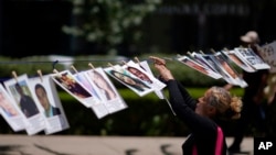 ARCHIVO - Una mujer cuelga el retrato de una persona desaparecida durante una protesta en la avenida Reforma exigiendo al gobierno localizar a sus seres queridos, en conmemoración del Día Internacional de los Desaparecidos, en la Ciudad de México, el 30 de agosto de 2023. 