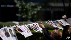 Una mujer cuelga un retrato de una persona desaparecida en una línea improvisada a lo largo de la Avenida Reforma, en conmemoración del Día Internacional de los Desaparecidos, en la Ciudad de México, el miércoles 30 de agosto de 2023.