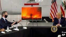 Presiden AS Donald Trump (kanan) mendengarkan penjelasan soal kebakaran hutan di California dari Gubernur Gavin Newsom di McClellan Park, California, Senin (14/9). 