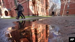 FILE - People walk between buildings, Dec. 17, 2024, on the campus of Harvard University in Cambridge, Mass.