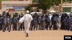 Anti-government protestor faces riot police last week in Khartoum (A. Ahmed/VOA).