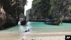 FILE - Long-tail boats sit near a small beach on Ko Phi Phi Leh, an island off the southwestern coast of Thailand, Dec. 5, 2016. The smaller of the Phi Phi Islands is a tourist hotspot for its beautiful water, party atmosphere and famed Maya Bay, where the movie "The Beach" was filmed. 