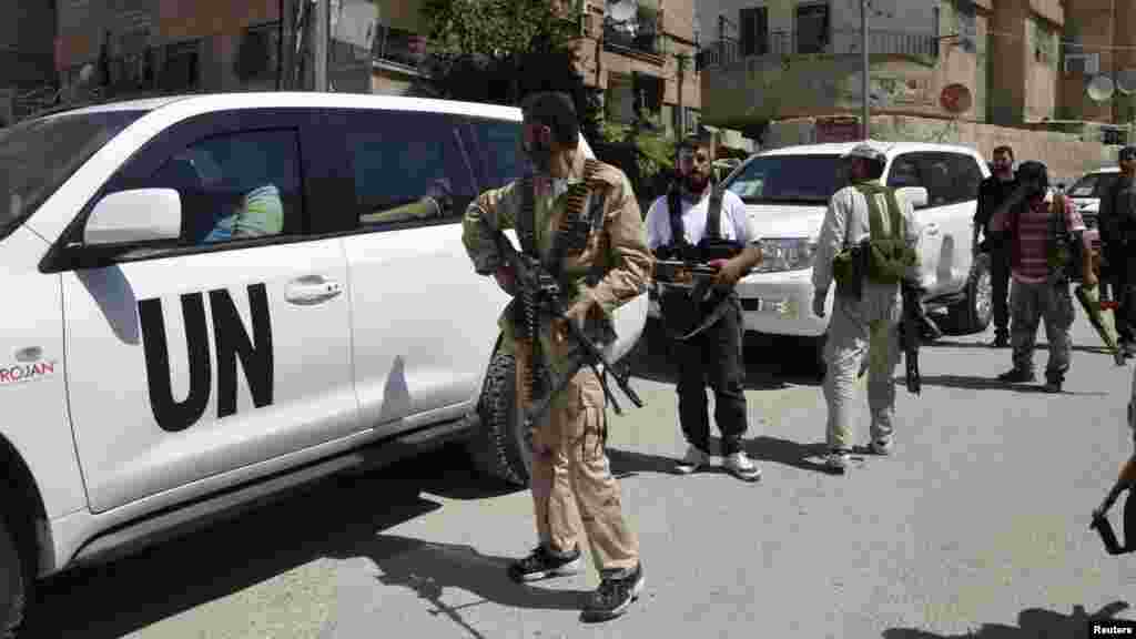 Free Syrian Army fighters carry their weapons as they escort U.N. vehicles carrying chemical weapons experts at the site of an alleged chemical weapons attack in a Damascus suburb, August 28, 2013. 