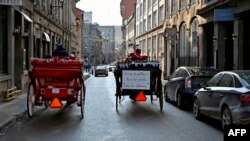 Dua kereta kuda melintas di jalan Old Montreal, Quebec, Kanada pada 22 Desember 2019. (Foto: AFP)