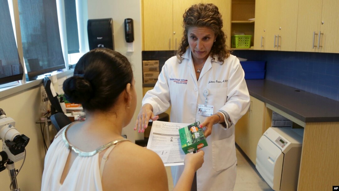 FILE- Nurse practitioner Juliana Duque gives a patient who is pregnant insecticide and and information about mosquito protection at the Borinquen Medical Center in Miami, Aug. 2, 2016.