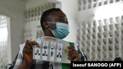 Une agente examine un bulletin de vote marqué alors que le décompte des voix est en cours à Abidjan, en Côte d'Ivoire, le 31 octobre 2020.