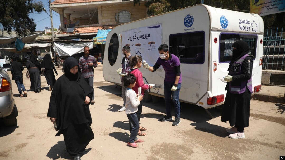 Seorang petugas lembaga swadaya masyarakat mengukur suhu warga sebagai pencegahan virus corona di Kota Kafr Takharim, Provinsi Idlib, 14 April 2020. 