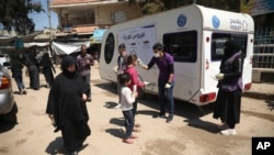 A member of a non-governmental aid organization measures temperature as a preventive measure for coronavirus in the town of Kafr Takharim, Idlib province, Syria, April 14, 2020. 