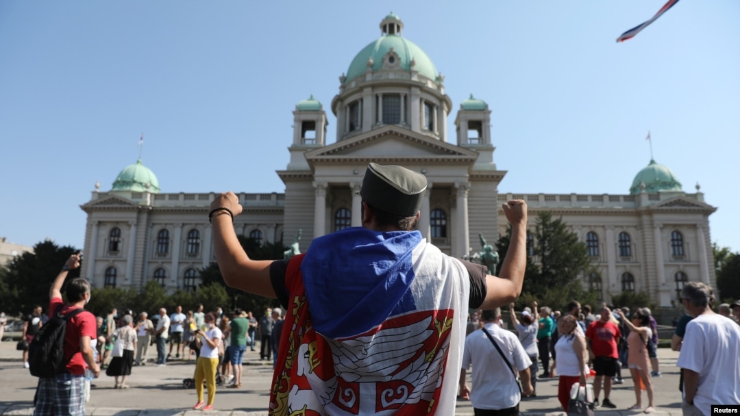 A protester raises his fists in front of the Serbian parliament during an anti-government rally, as deputies attend the first session of the National Assembly after June's national election, Aug. 3, 2020.