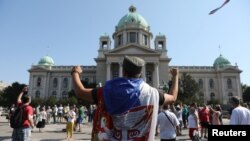 A protester raises his fists in front of the Serbian parliament during an anti-government rally, as deputies attend the first session of the National Assembly after June's national election, Aug. 3, 2020.