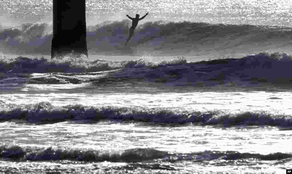 A surfer rides a wave at New Brighton Beach in Christchurch, New Zealand.