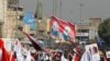 Iraqis, including supporters of Hashid Shaabi (Popular Mobilization Forces), hold flags and placards depicting senior Iranian military commander General Qassem Soleimani and Iraqi militia commander Abu Mahdi al-Muhandis, in Baghdad, Jan. 3, 2021.