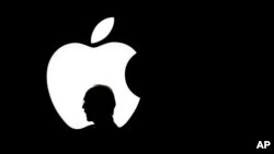 FILE - A man walks past the Apple logo during a product display for Apple TV following an Apple event in San Francisco, Sept. 9, 2015.