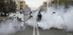 FILE - Members of firefighters wear protective face masks, amid fear of coronavirus disease (COVID-19), as they disinfect the streets, ahead of the Iranian New Year Nowruz, March 20, in Tehran, March 18, 2020.