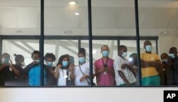 FILE — In this Feb, 17 2021 file photo, health care workers look through a window at a hospital in Khayelitsha, Cape Town, South Africa during the rollout of the first batch of Johnson and Johnson vaccines in the country.