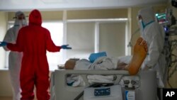 Medics wearing protective suits consult as they treat a COVID-19 patient in intensive care at the Moscow City Clinical Hospital 52, in Moscow, Russia, Oct. 19, 2021.
