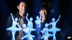 Tomoaki Ishizuka, left, and Yurika Yonekura watch the hologram of Japanese skater Yuzuru Hanyu, center, with ballet dancers with their scanned faces attached at newly opened Hologram Dance Theater at Madame Tussauds in Tokyo, April 28, 2016.