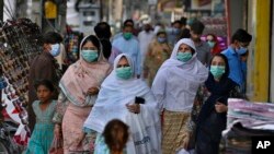 FILE - A family wearing masks to help curb the spread of the coronavirus visits a market in Rawalpindi, Pakistan, June 2, 2020. (