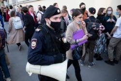 A police officer patrols an area as supporter of 'DOXA' magazine editors gather at the court building in Moscow, Russia, Apr. 14, 2021.