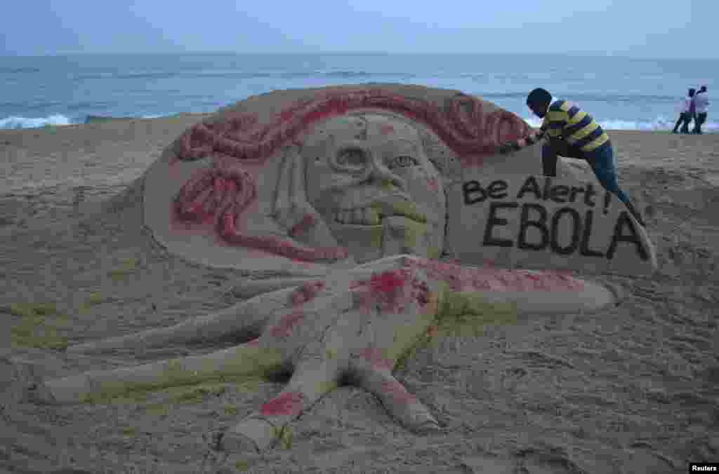 Indian sand artist Sudarshan Pattnaik works on a sand sculpture that shows a message about Ebola on a beach at Puri, in the eastern Indian state of Odisha. 