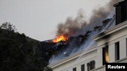 Flames and smoke rise over a roof as a fire at the parliament flares up again, in Cape Town, South Africa, Jan. 3, 2022. 