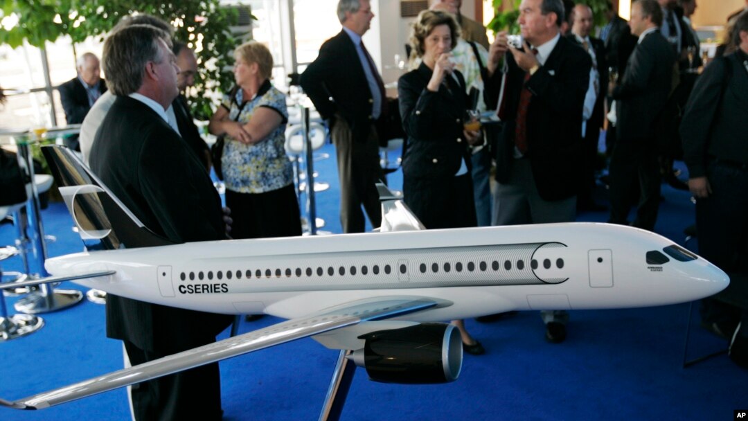FILE - People gather around a model of C Series Bombardier airplane on the eve of the Farnborough aerospace show, Farnborough, England, July 13, 2008. Boeing has accused Bombardier of receiving government subsidies that let it engage in “predatory pricing.”
