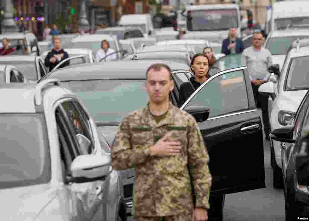 People stand during a minute of silence to mark the Defenders of Ukraine Day in Kyiv.