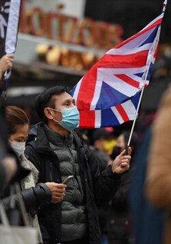 FILE - Protesters gather with flags to mourn the loss of Hong Kong's political freedoms, in Leicester Square, central London, Dec. 12, 2020.