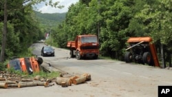 A car passes by trucks used as barricades after Kosovo police cleared the road near Zubin Potok, Kosovo, May 28, 2019.