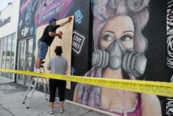 Ariel Bernhardt boards up windows at a small business called Drone Nerds, May 31, 2020, in Miami, in the aftermath of protests over the death of George Floyd.