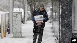 A person carries boxes as snow falls over the northern New Jersey region during a rare October snowstorm October 29, 2011.