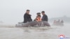 This recent undated photo released by North Korea's official Korean Central News Agency (KCNA) via KNS on July 31, 2024 shows North Korea's leader Kim Jong Un (L) riding in a dingey through flood waters as he inspects the area for damage after record-brea