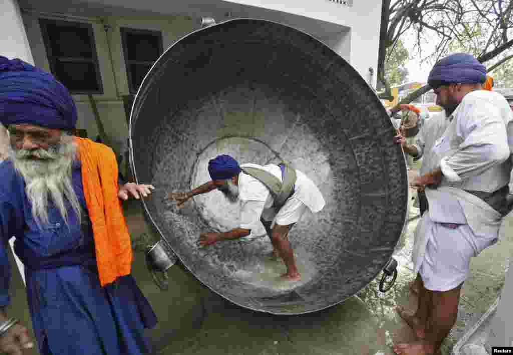 Seorang pria membersihkan panci besar untuk menyiapkan minuman non-alkohol selama perayaan festival Hola Mohalla di kota Anandpur Sahib, negara bagian Punjab, India utara. &quot;Hola Mohalla&quot; adalah festival yang dirayakan oleh kaum Sikh dari seluruh India, yang dirayakan bersamaan dengan festival agama Hindu Holi.