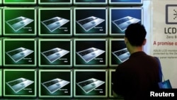 FILE - A visitor looks at ASUS computer screens at the Computex trade show in Taipei.