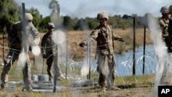 Sejumlah tentara AS memasak kawat berduri di sepanjang pinggiran sungai Rio Grande dekat jembatan Juarez-Lincoln di perbatasan AS-Meksiko, di Loredo, Texas, 16 November 2018. 