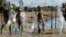 FILE - In this Nov. 16, 2018, photo, members of the U.S. military install multiple tiers of concertina wire along the banks of the Rio Grande near the Juarez-Lincoln Bridge at the U.S.-Mexico border in Laredo, Texas. 