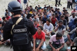 Seorang polisi berjaga setelah sejumlah pria dari etnis Rohingya mereka mendarat di Aceh Besar, Minggu, 8 Januari 2023. (Foto: AP/Muhammad Ahyar)