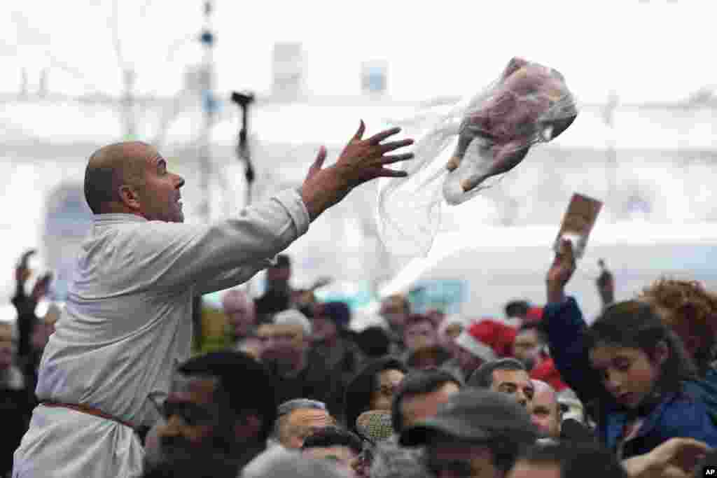 A butcher throws a turkey for sale to customers during the annual Christmas Meat Auction at Smithfield Market in London.