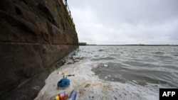 Sampah termasuk botol plastik bekas dan bungkus makanan, mengambang di permukaan air di Danau Laut di West Kirby di barat laut Inggris, 22 April 2024. (Paul ELLIS / AFP)