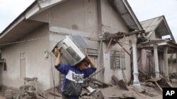 A man carries a television as he evacuates to a safer place following the eruption of Mount Semeru in Lumajang district, East Java province, Indonesia, Dec. 6, 2021. 